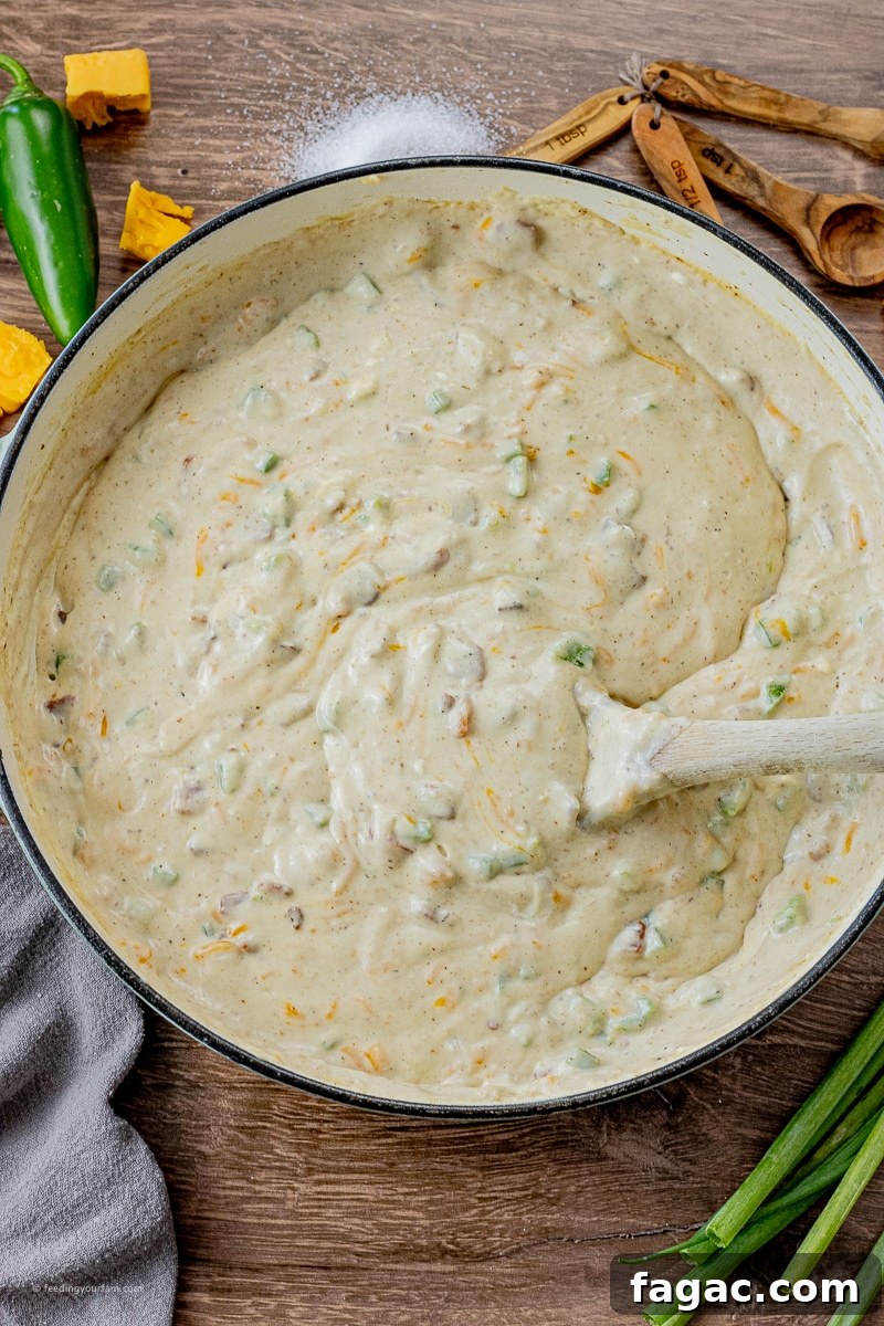 Jalapeño Popper Macaroni and Cheese Recipe 7 sauce made with milk, flour, jalapenos, cream cheese and cheddar cheese in a large pan