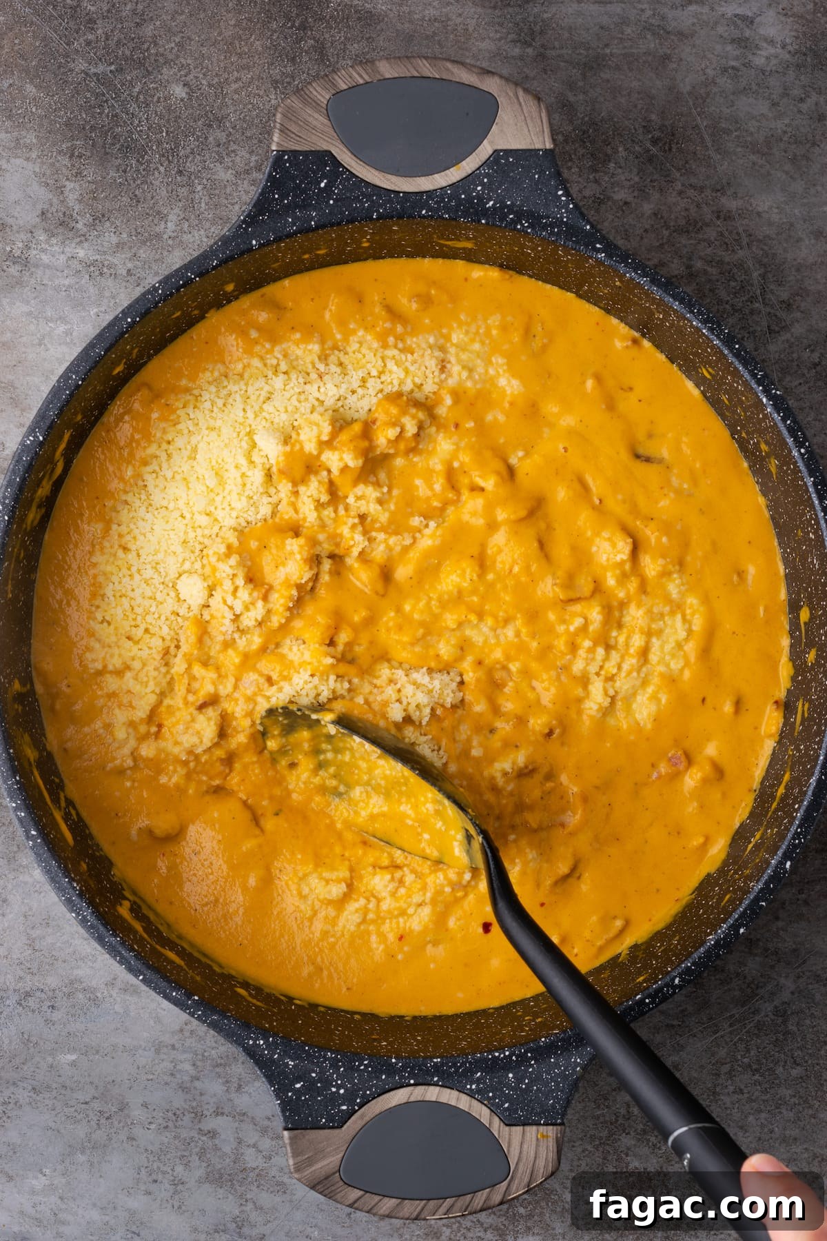 Cooked farfalle pasta is stirred into pumpkin cream sauce with bacon in a cast iron skillet.