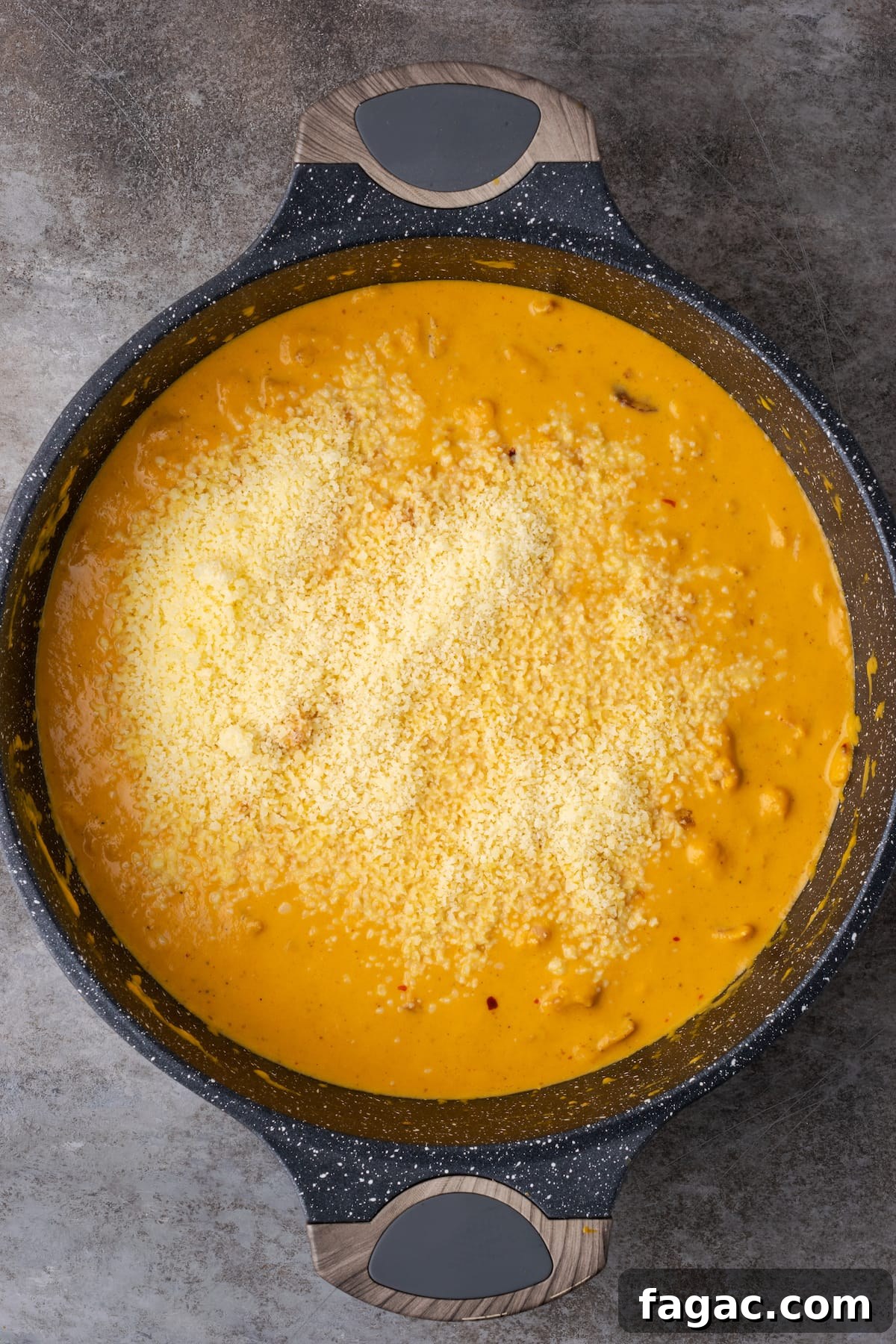 Parmesan cheese is added to the pumpkin cream sauce in a cast iron skillet.