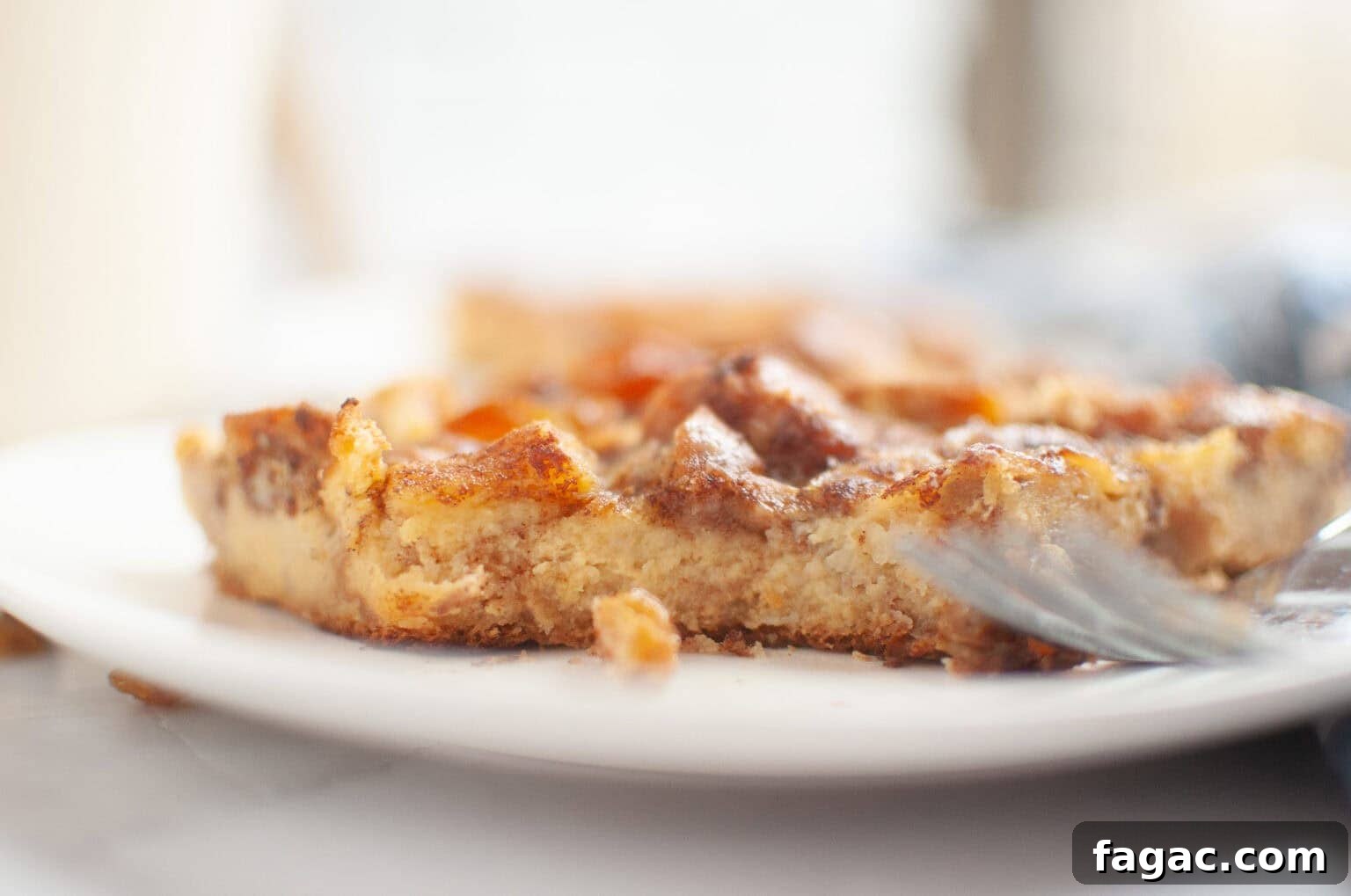 23 Classic Casseroles That Taste Like Grandma’s Comfort Cooking 11 A close-up of a partially eaten piece of Cinnamon Roll Casserole on a white plate, with a fork resting beside it.