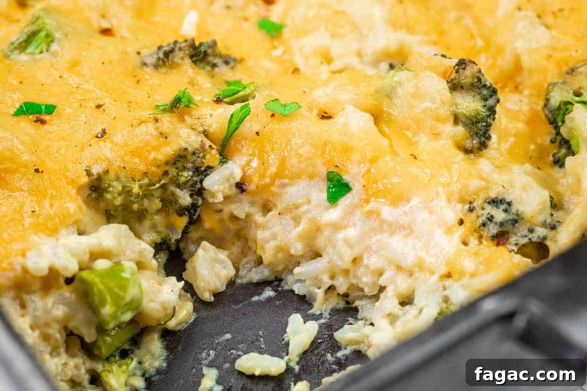 23 Classic Casseroles That Taste Like Grandma’s Comfort Cooking 13 Close-up of a cheesy broccoli and rice casserole in a baking dish, with a serving removed, showing melted cheese, rice, broccoli, and garnished parsley.