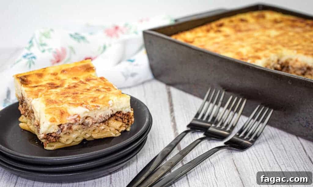 23 Classic Casseroles That Taste Like Grandma’s Comfort Cooking 14 A square piece of pastitsio served on a stack of black plates with three forks and a rectangular baking tray filled with the same pasta on the side.