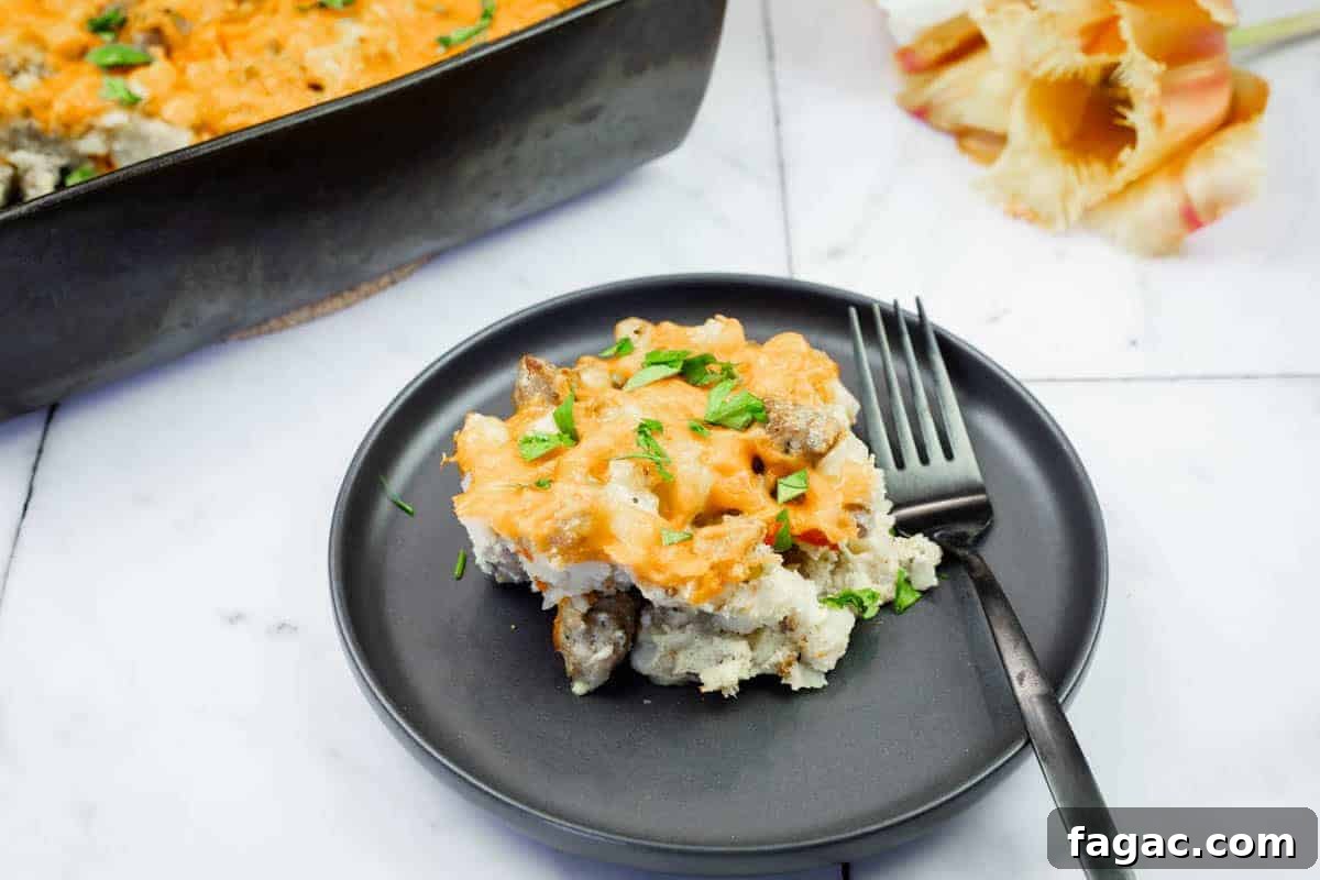 23 Classic Casseroles That Taste Like Grandma’s Comfort Cooking 3 A serving of Sausage-Hash Brown Breakfast Casserole on a black plate with a fork, next to a baking dish and pasta shells on a marble surface.