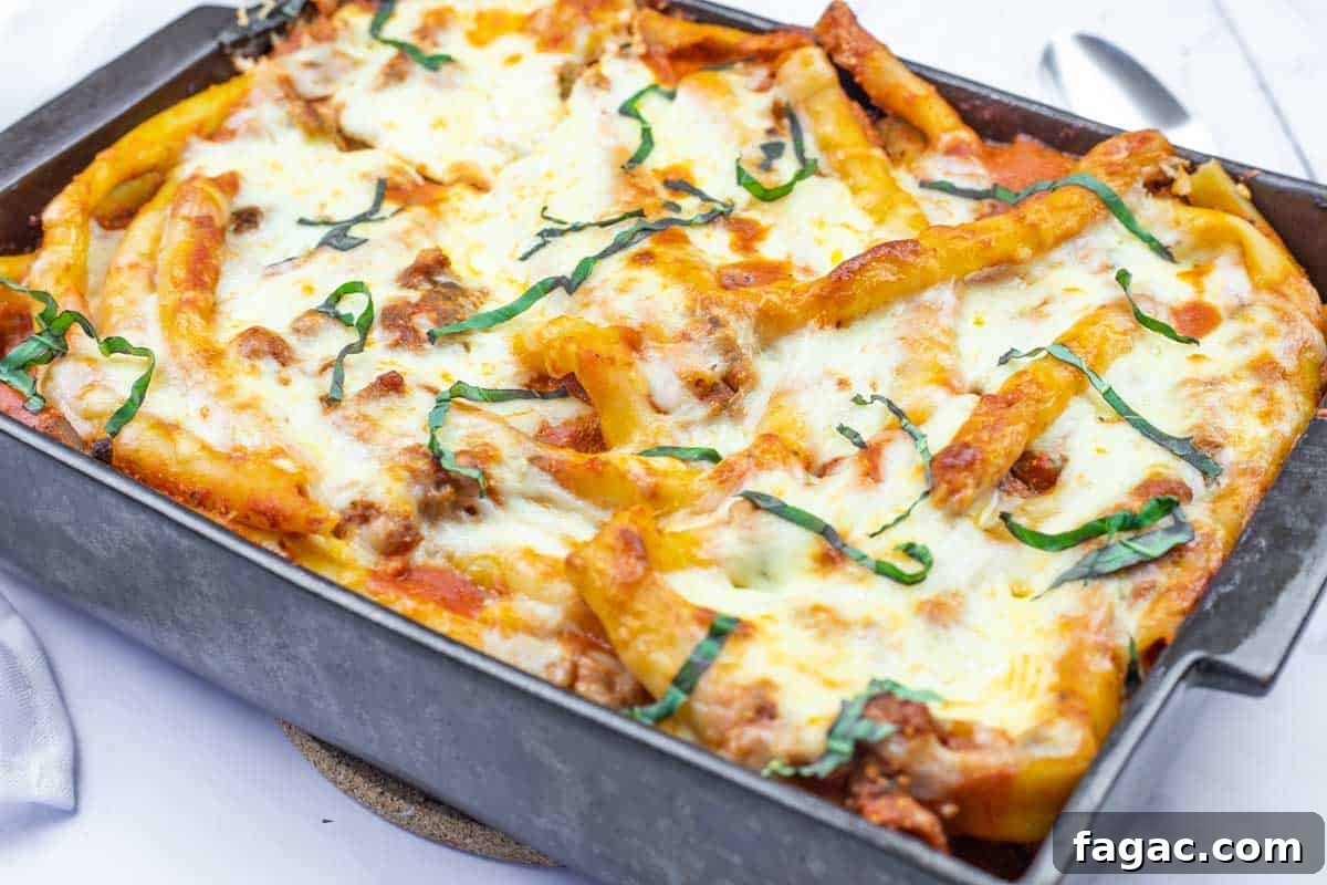 23 Classic Casseroles That Taste Like Grandma’s Comfort Cooking 4 Baked Ziti Casserole dish in a rectangular pan topped with melted cheese, tomato sauce, ground meat, and fresh basil strips.