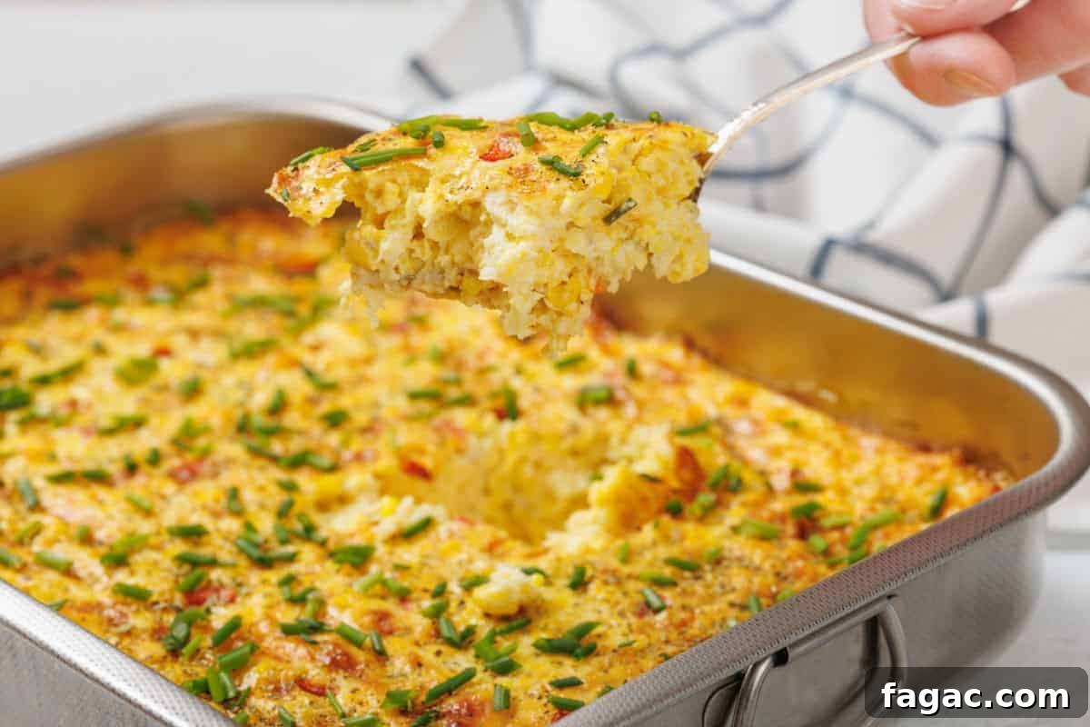 23 Classic Casseroles That Taste Like Grandma’s Comfort Cooking 10 A Corn Pudding Casserole topped with chopped chives in a metal baking dish, with a portion being lifted out on a serving spatula.