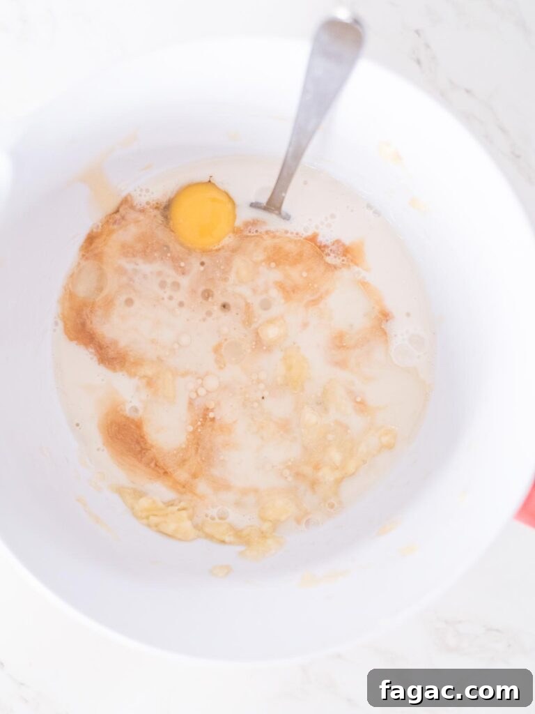 coconut oil added to the remaining wet ingredients for banana muffins in a mixing bowl