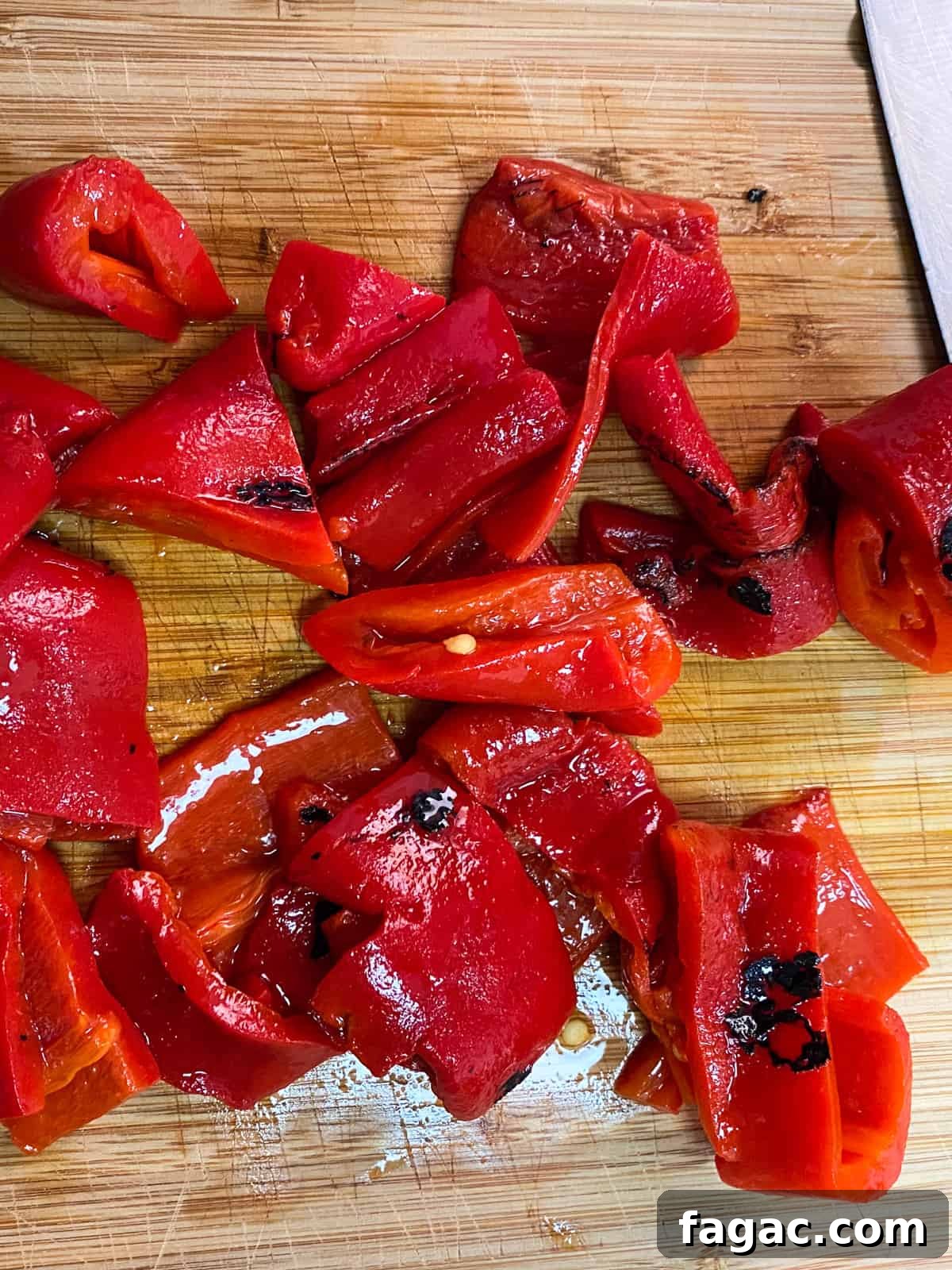 photo of roasted red peppers being chopped on a board.
