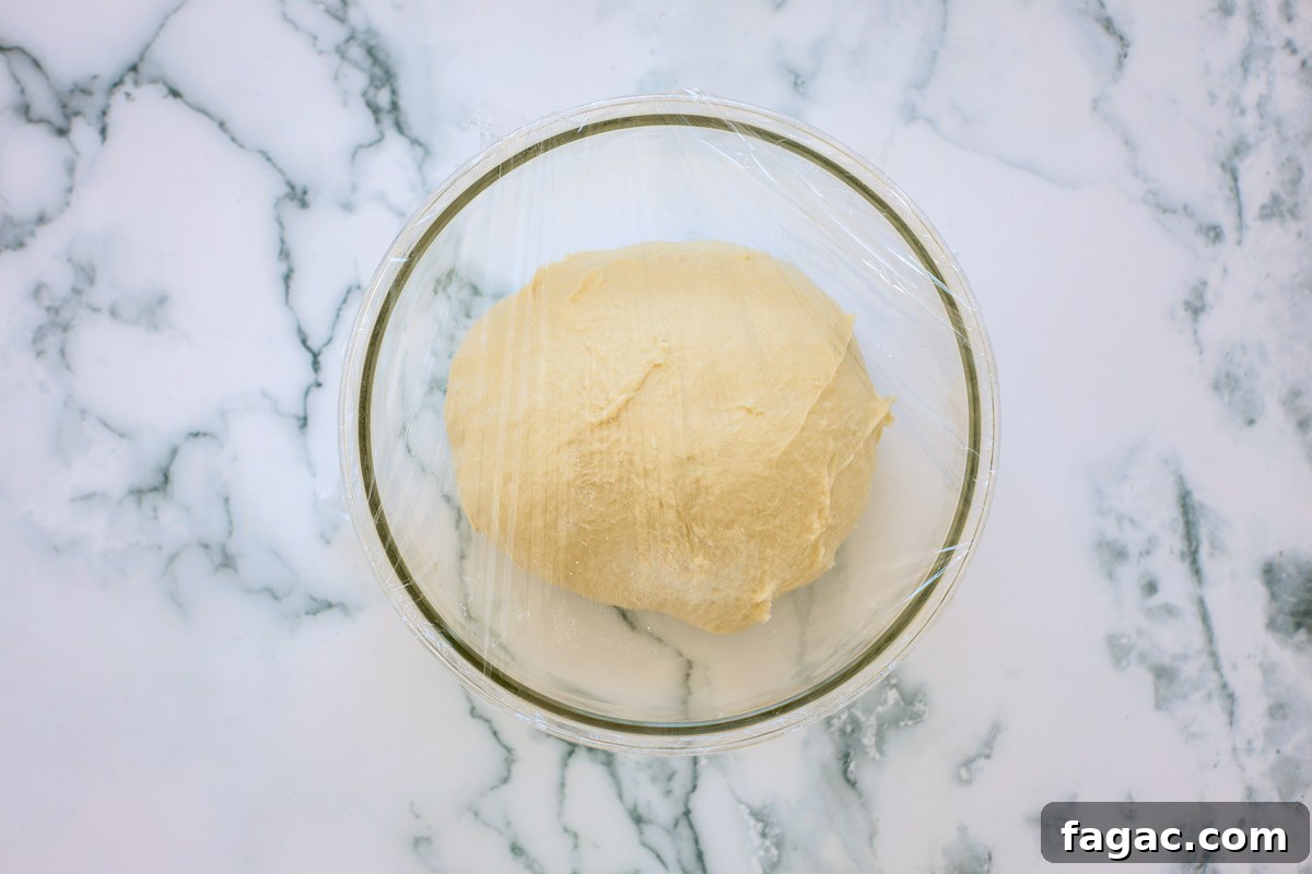 Sourdough Buttermilk Bread Recipe: Tangy Artisan Loaf Guide 6 Formed dough in a glass bowl covered with plastic wrap.