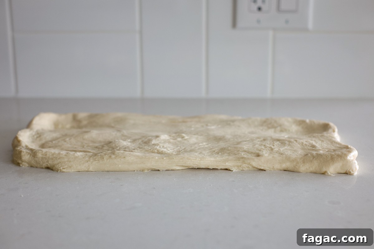 Sourdough Buttermilk Bread Recipe: Tangy Artisan Loaf Guide 8 Dough on a counter opened into a rectangle.
