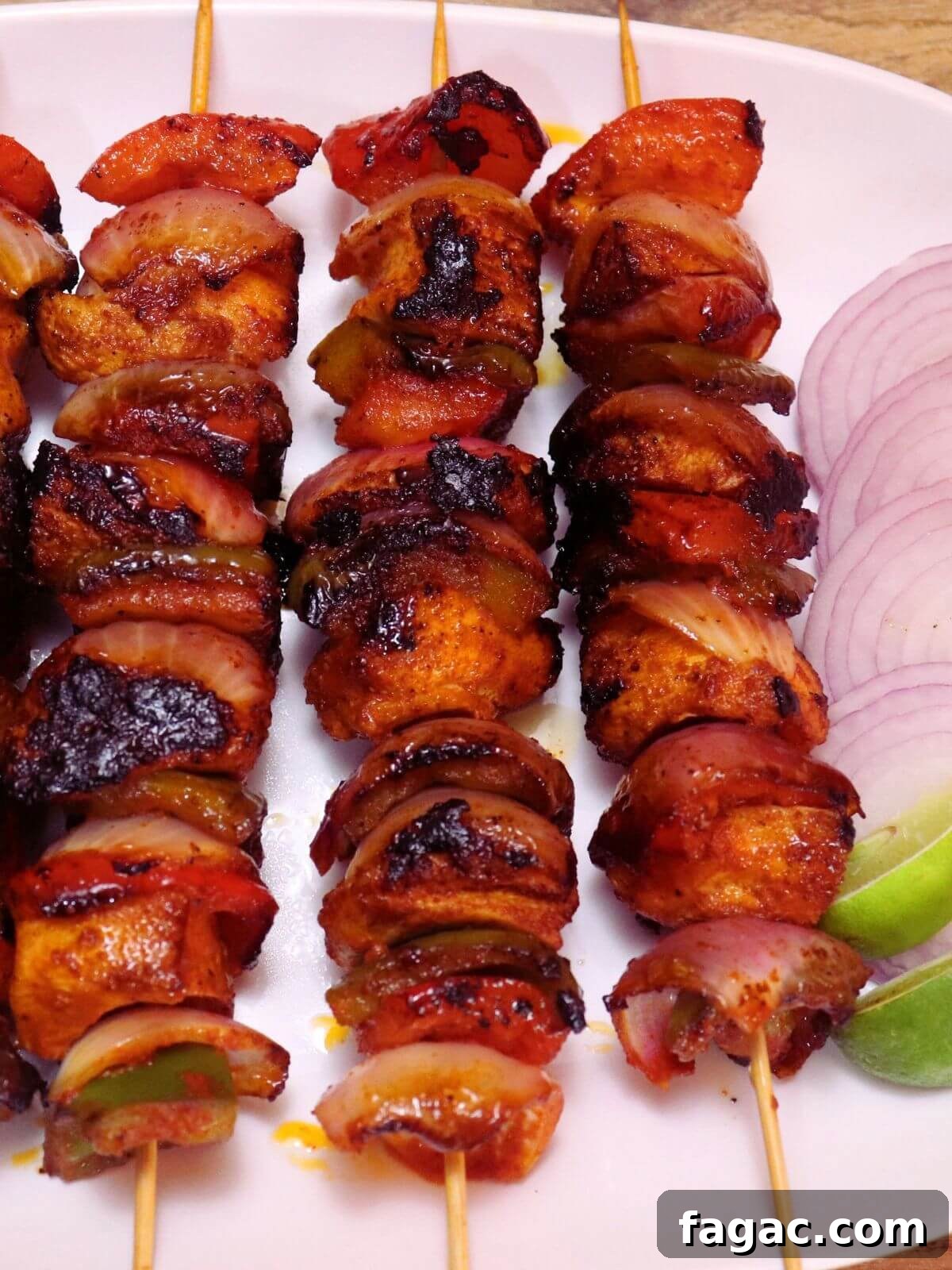 Chicken Shashlik Kebab Recipe: Juicy Grilled Indian-Style Skewers 2 close-up of chicken shashlik. Three chicken shashlik skewers placed on a white plate. It is served with onion slices and lemon wedges.