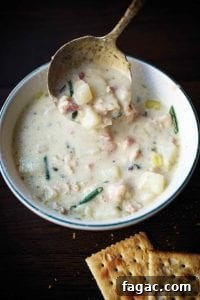 A bowl of creamy New England clam chowder with clams, potatoes, leeks, shallots, cream, and chives