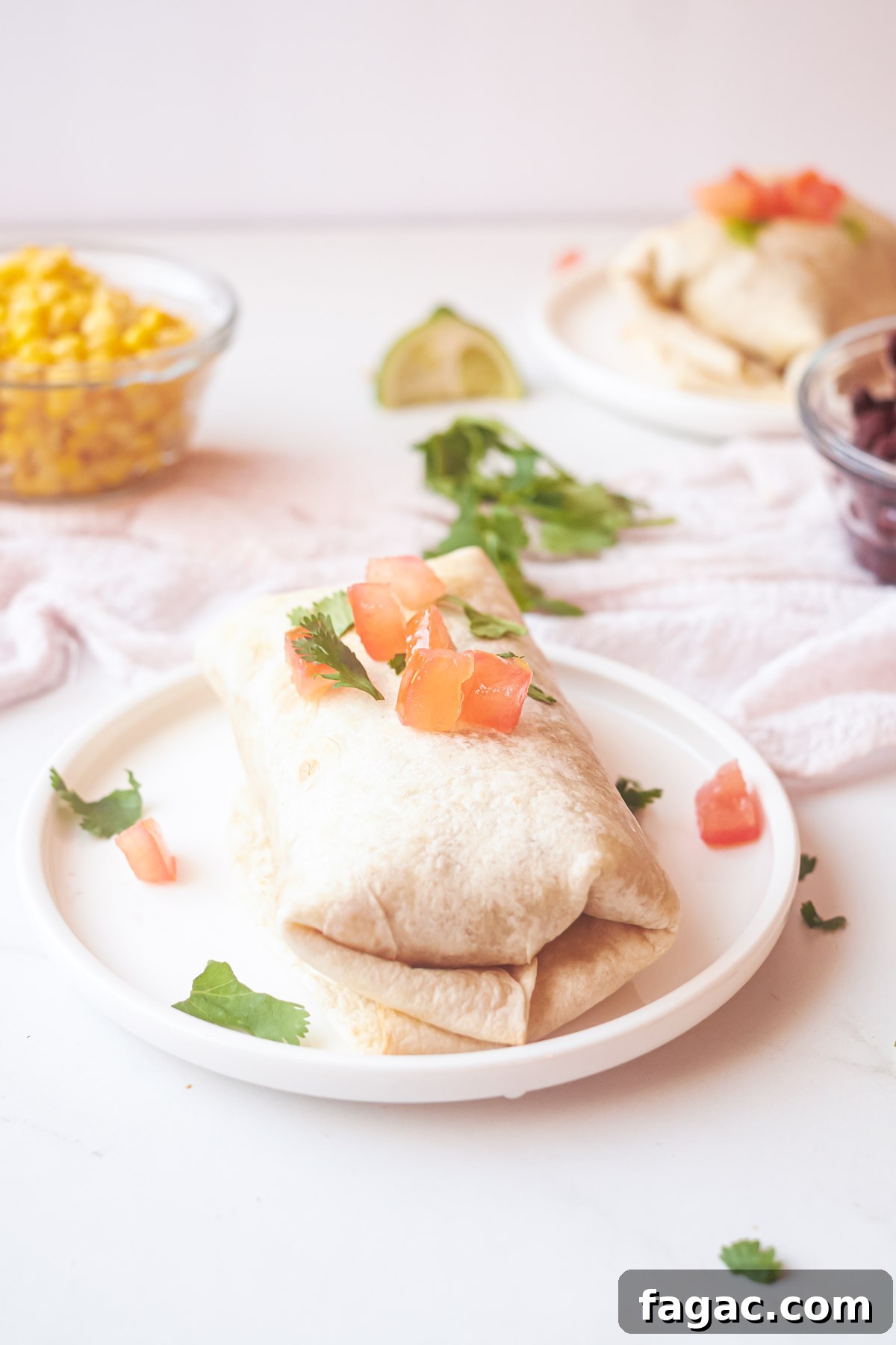 Crispy Air Fryer Breakfast Burrito Recipe 9 a completed air fryer burrito on a plate topped with diced tomatoes and cilantro