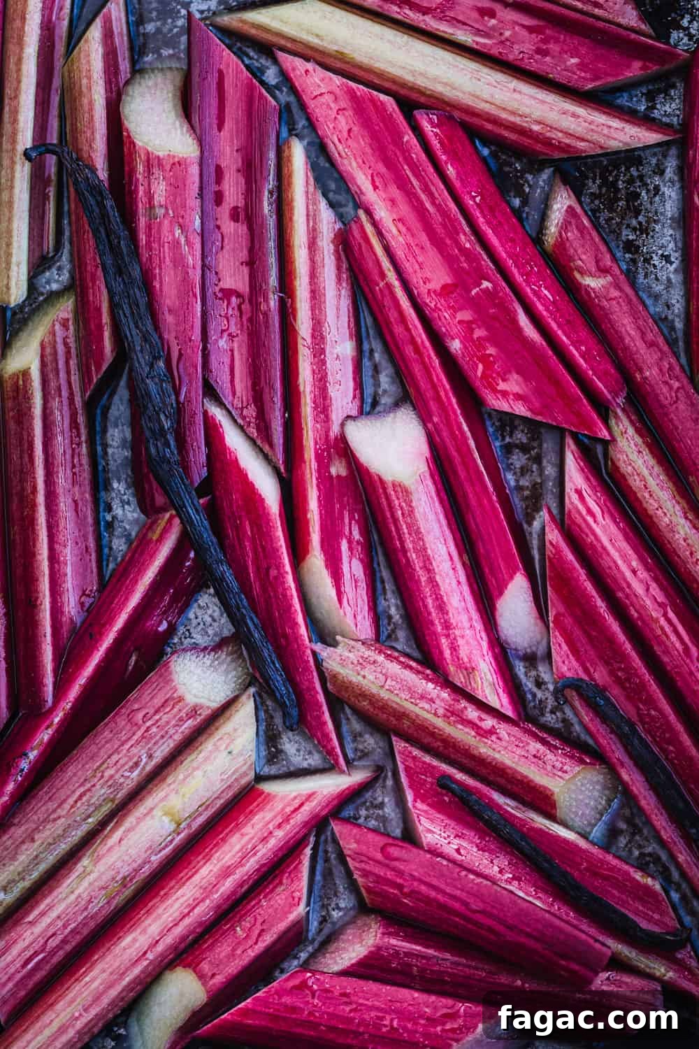 Raw rhubarb stalks sliced on a tray with vanilla and ready to be cooked in the oven.