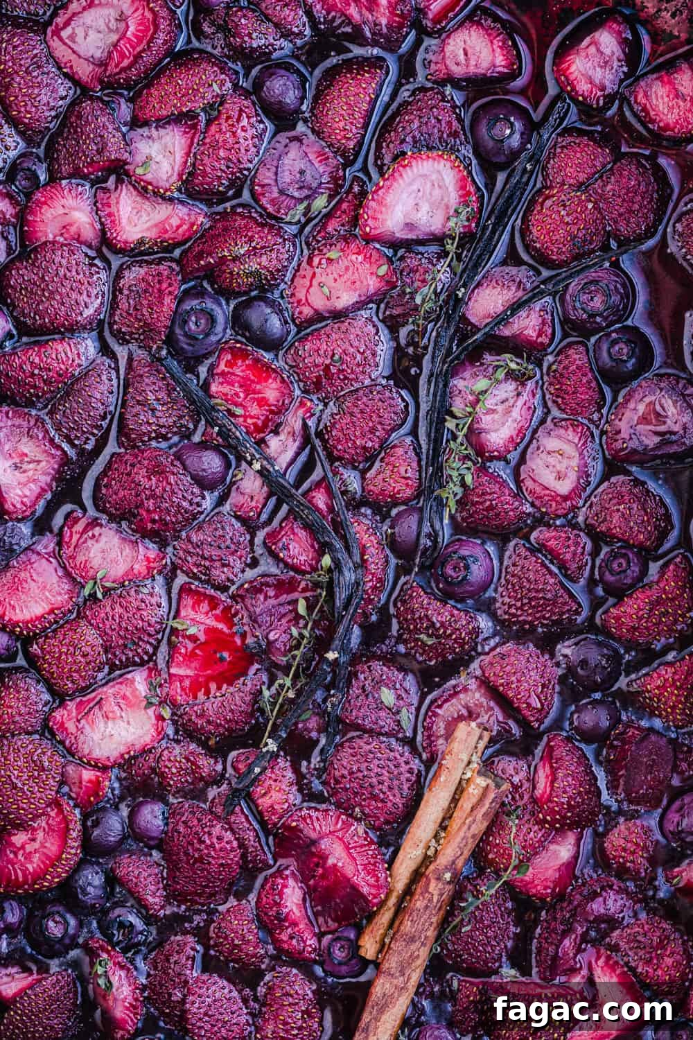 cooked fruit! strawberries and blueberries all cooked and just out of the oven with vanilla beans, thyme and cinnamon sticks, overhead shot.