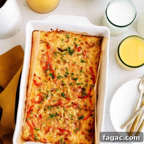 Baked casserole with red peppers and herbs in a white dish, surrounded by eggs, apples, orange juice, and a glass of milk on a table.