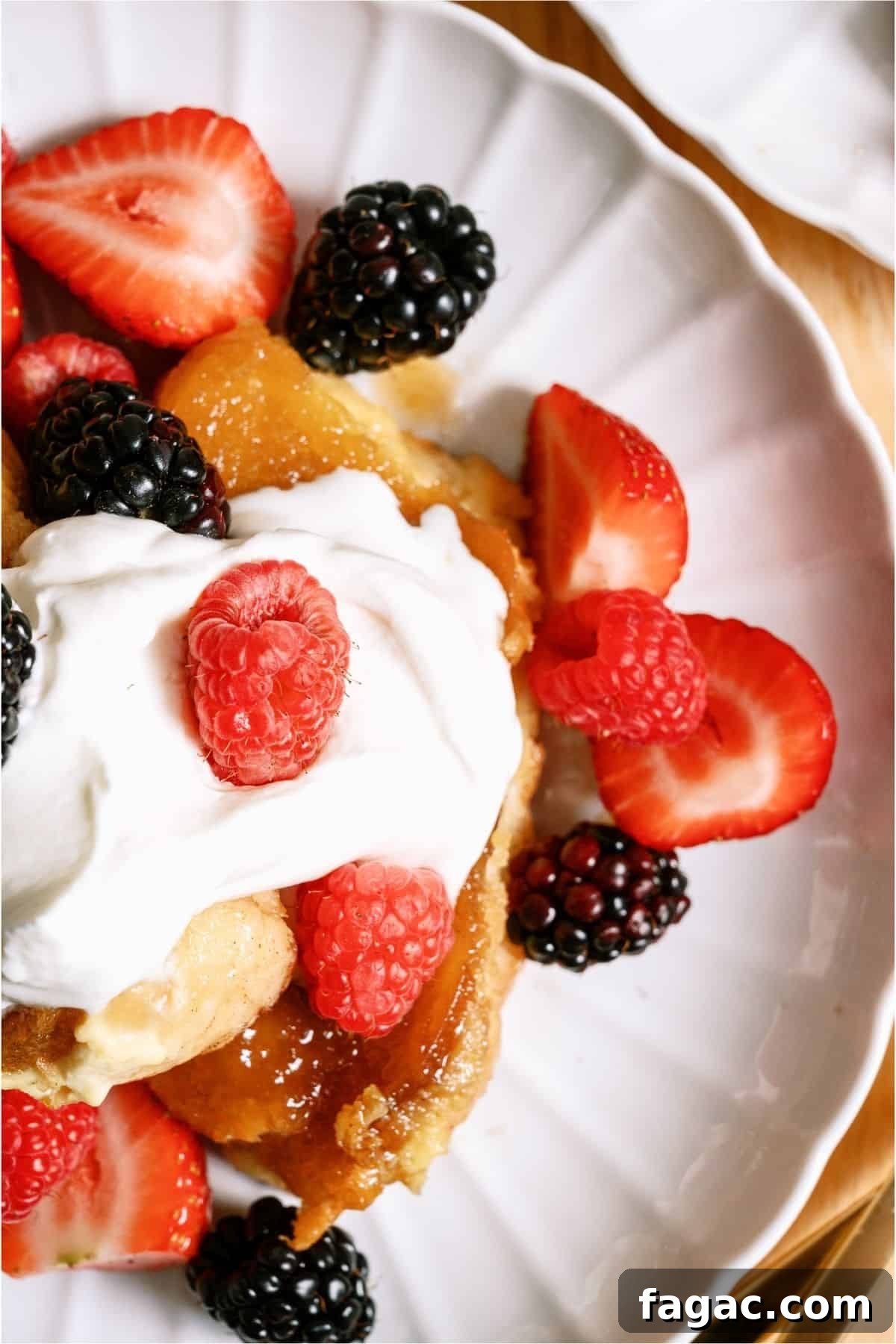 Top view of a serving of Overnight Creme Brulee French Toast Bake on a plate topped with whip cream and berries.