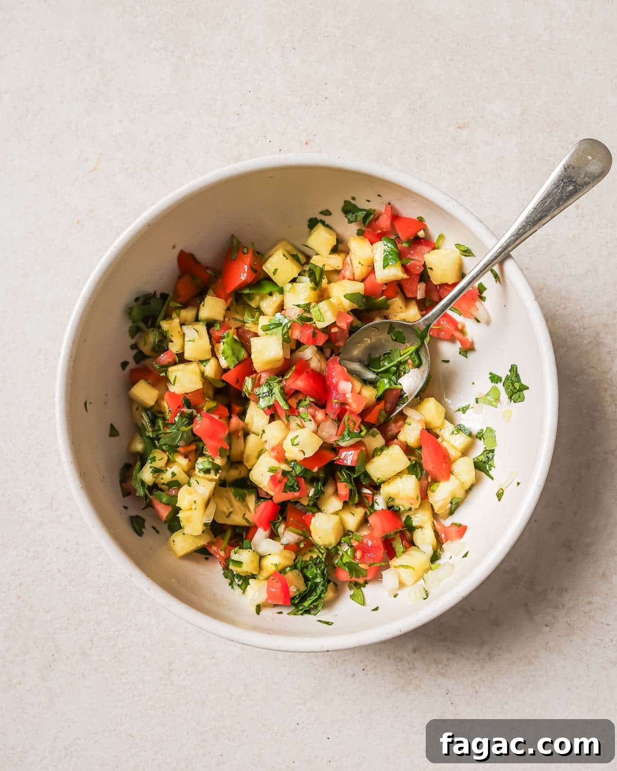 Crispy Pan-Seared Salmon with Fresh Pineapple Salsa 5 Pineapple salsa in a white bowl with a spoon.
