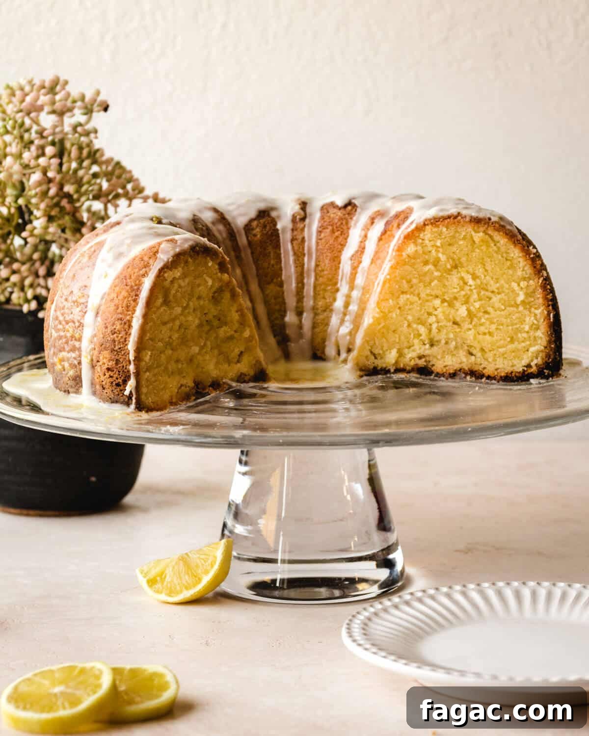 Authentic Italian Lemon Pound Cake Recipe with Zesty Glaze 2 Half a lemon pound cake with a glaze drizzled over it sitting on a cake stand.
