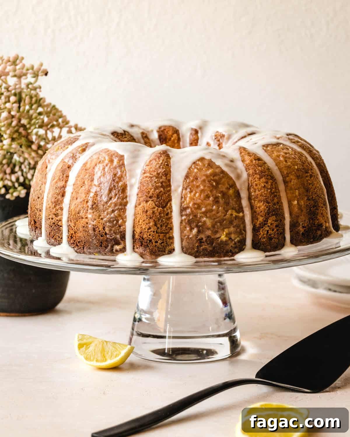 Authentic Italian Lemon Pound Cake Recipe with Zesty Glaze 8 Italian lemon cake with glaze sitting on a glass cake display with lemon wedges around the base.