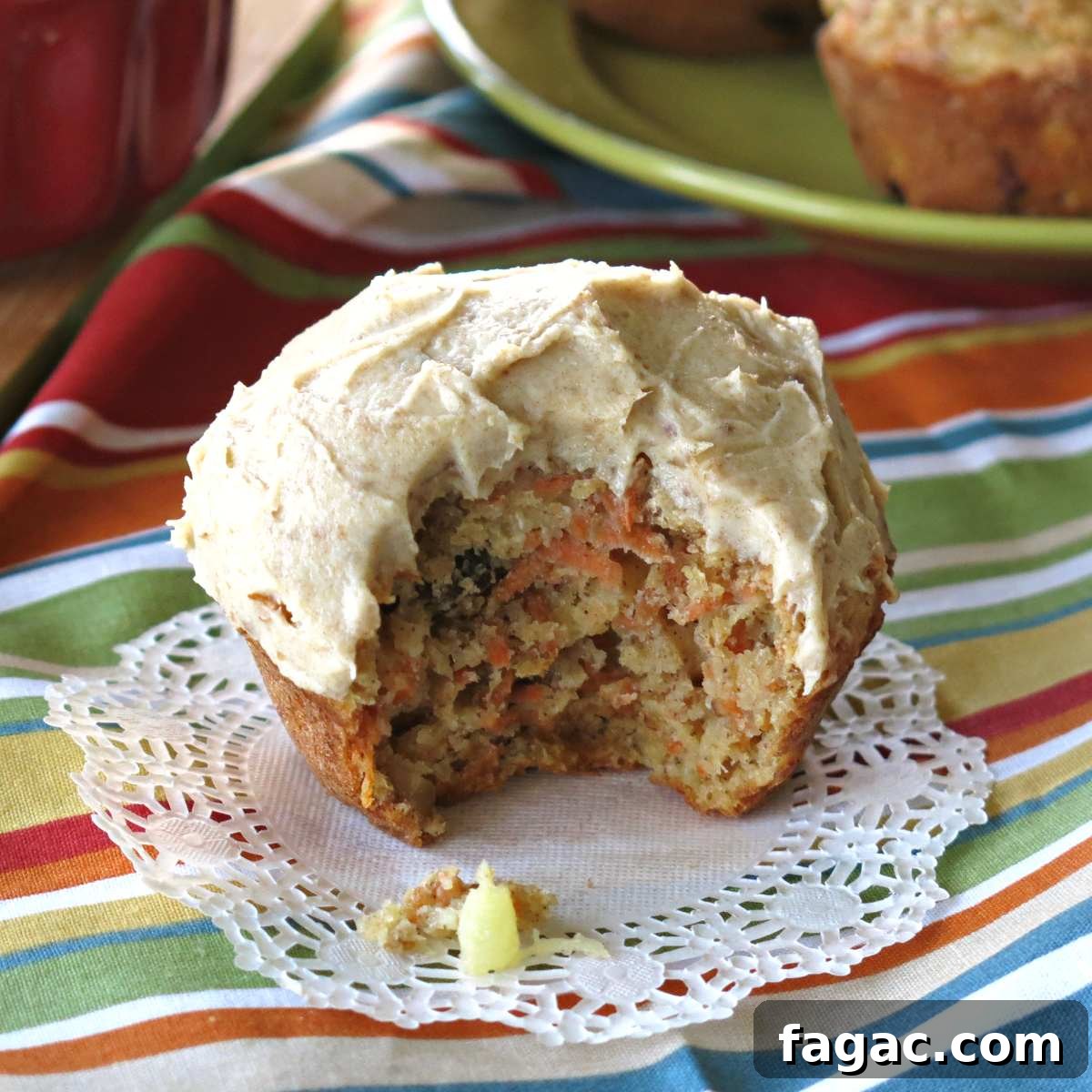 Bite taken out of healthy pineapple carrot cake muffin with cream cheese frosting.