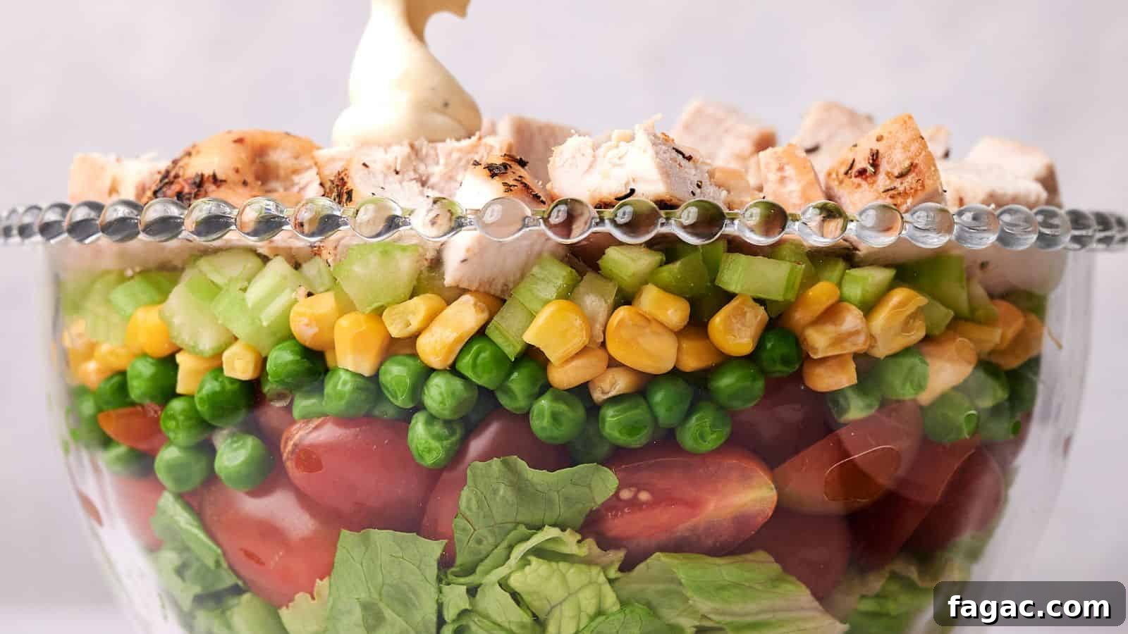 21 Easter Salad Ideas to Refresh Your Holiday Table 11 A clear glass bowl layered with lettuce, cherry tomatoes, green peas, corn, diced celery, and topped with chunks of grilled chicken, garnished with a dollop of mayonnaise.