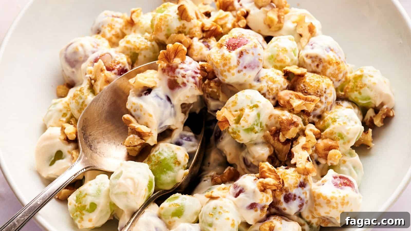 21 Easter Salad Ideas to Refresh Your Holiday Table 12 A bowl of grape salad with green and red grapes coated in creamy dressing, topped with chopped walnuts and brown sugar, with a spoon for serving.