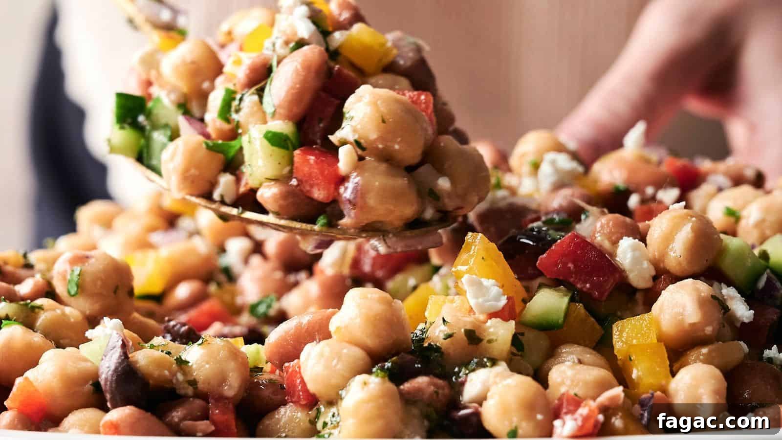 21 Easter Salad Ideas to Refresh Your Holiday Table 20 A spoonful of chickpea salad with chopped cucumbers, tomatoes, peppers, parsley, and feta cheese being served from a bowl.