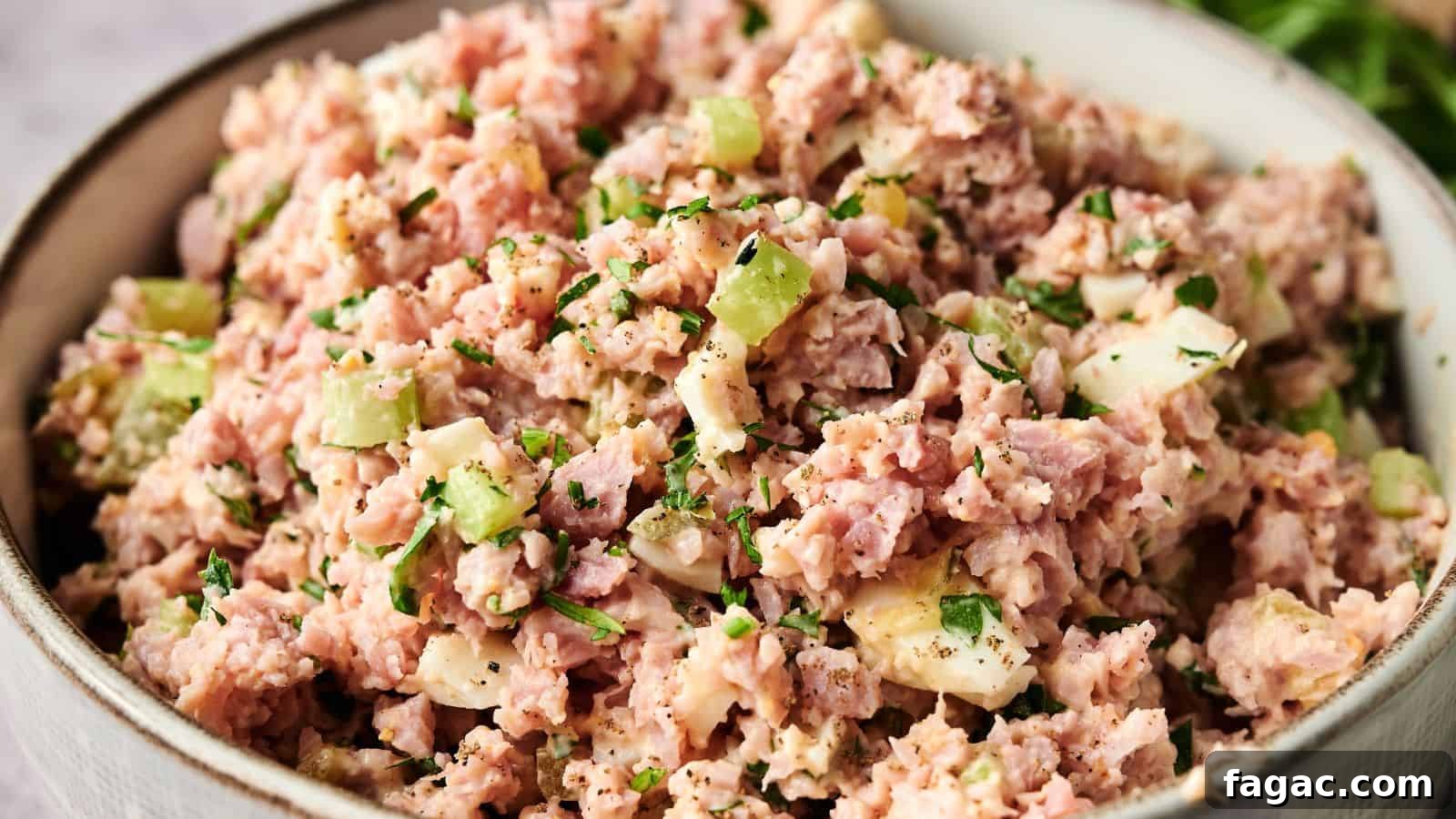 21 Easter Salad Ideas to Refresh Your Holiday Table 22 A bowl filled with ham salad, containing chopped ham, celery, hard-boiled eggs, and herbs, mixed with mayonnaise.
