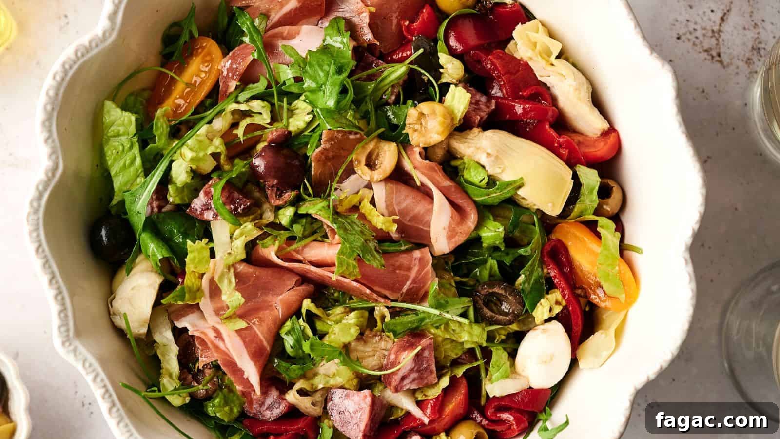 21 Easter Salad Ideas to Refresh Your Holiday Table 5 A bowl of salad with mixed greens, prosciutto, cherry tomatoes, olives, artichokes, and roasted red peppers.