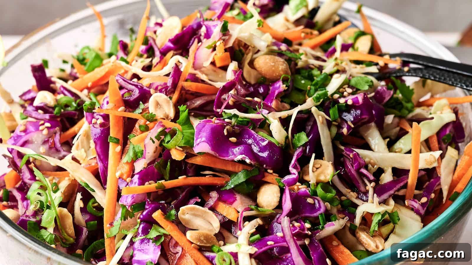 21 Easter Salad Ideas to Refresh Your Holiday Table 7 A bowl of colorful coleslaw with shredded purple and green cabbage, carrots, chopped peanuts, and greens, mixed with dressing.