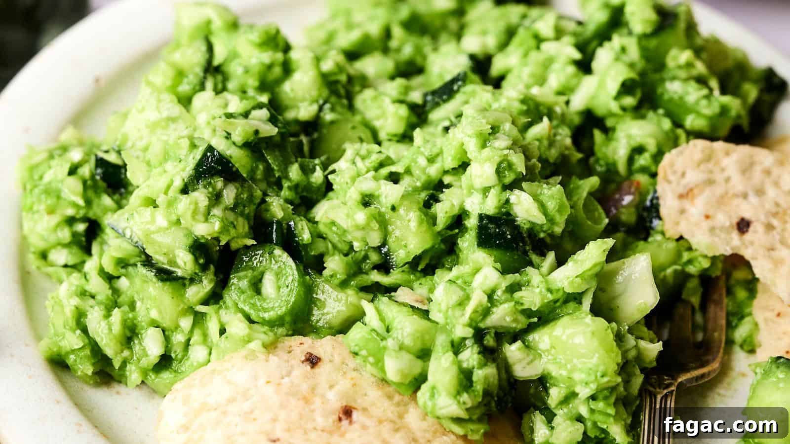 21 Easter Salad Ideas to Refresh Your Holiday Table 8 A close-up of a plate with bright green guacamole, chopped vegetables, and tortilla chips on the side.