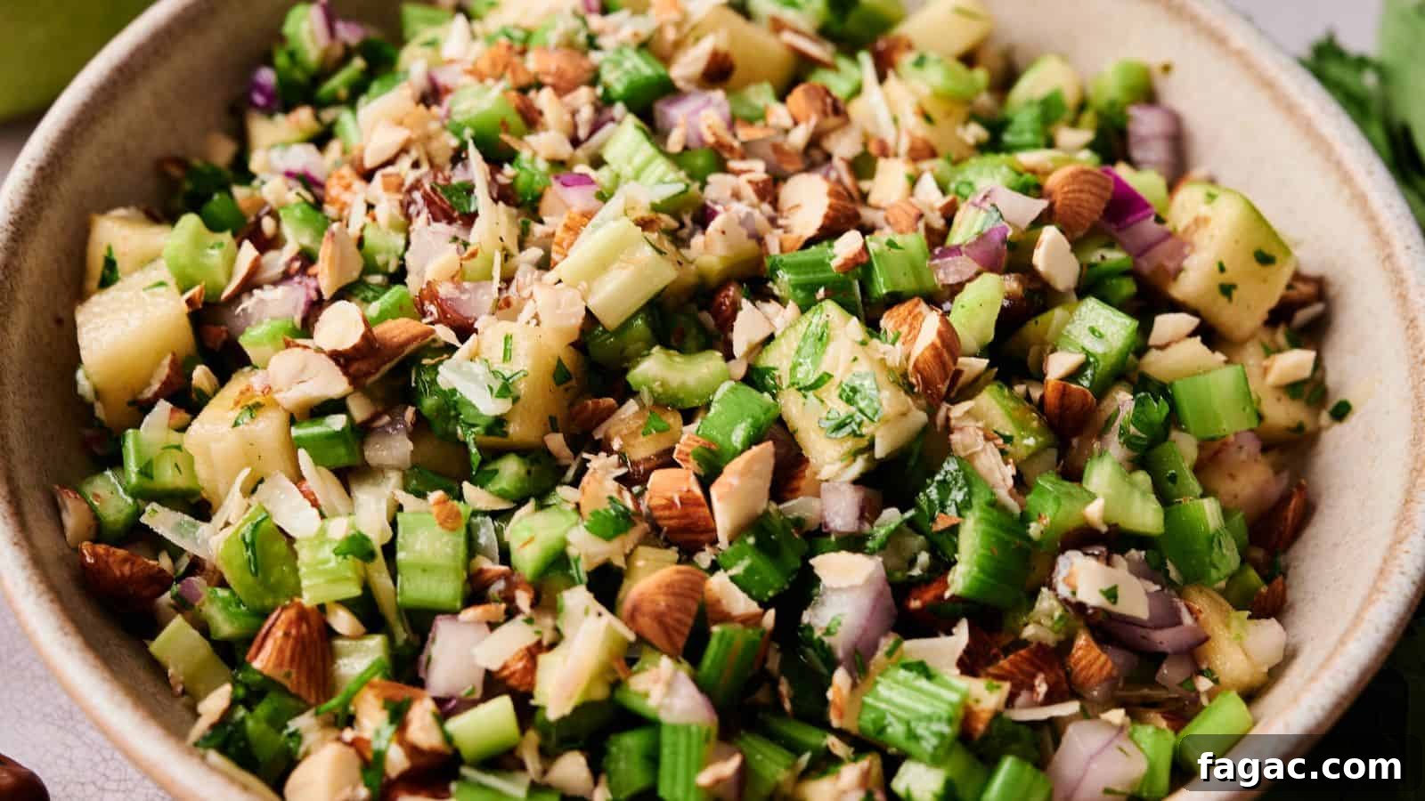 21 Easter Salad Ideas to Refresh Your Holiday Table 10 A bowl filled with chopped celery, red onion, apples, almonds, and fresh herbs.