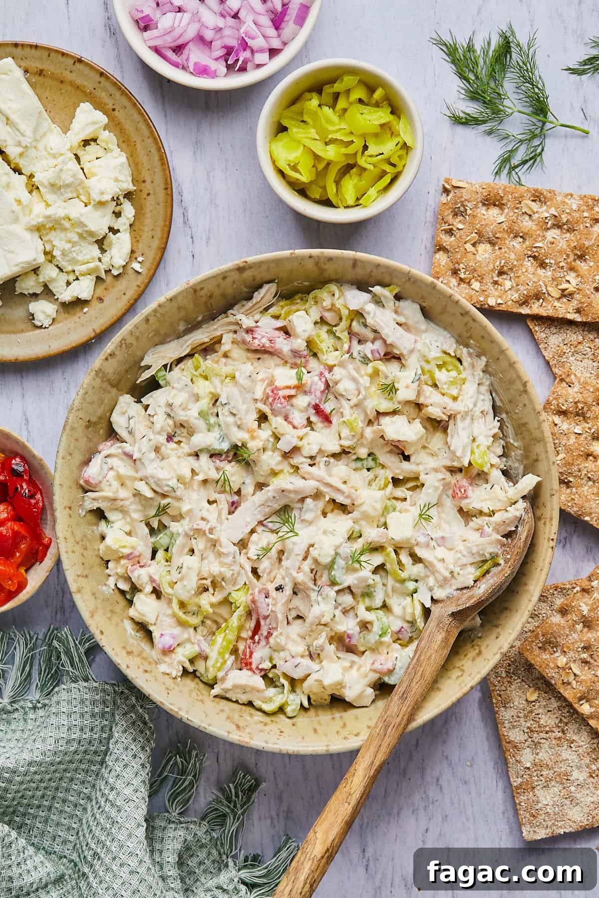 feta chicken salad in a bowl surrounded by crackers and ingredients