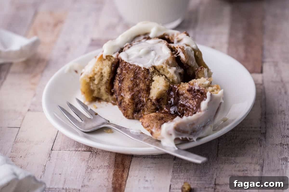 Soft and Fluffy Gluten-Free Cinnamon Rolls Without Xanthan Gum 8 Gluten-Free Cinnamon Roll on a plate with forkful taken out showing buttery cinnamon inside.