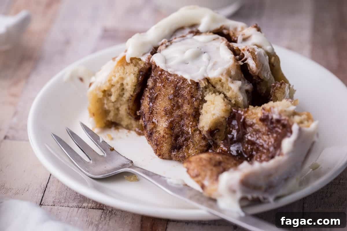 Soft and Fluffy Gluten-Free Cinnamon Rolls Without Xanthan Gum 4 Gluten-Free Cinnamon Roll on a plate with forkful taken out showing buttery cinnamon inside.
