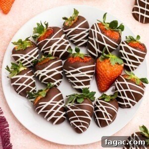 Chocolate covered strawberries on a white plate sitting on a pink table.