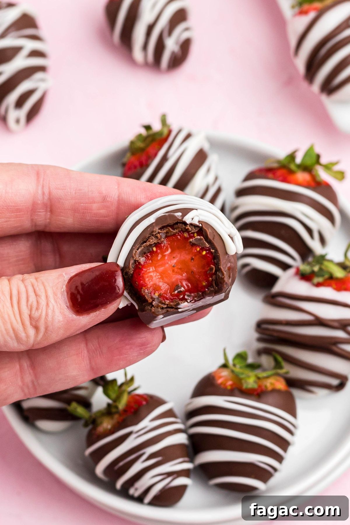 How to Make Chocolate-Covered Strawberries 7 One chocolate dipped strawberry being held after a bite has been removed showing the center.