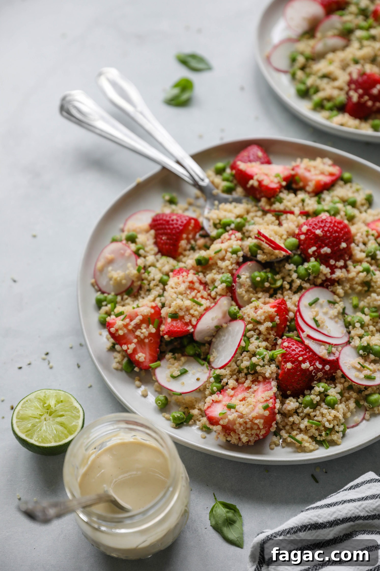 Fresh Strawberry Quinoa Salad with Lime Tahini Dressing 9 Strawberry Quinoa Salad served on plate with forks with blue and white striped towel with zesty lime tahini dressing