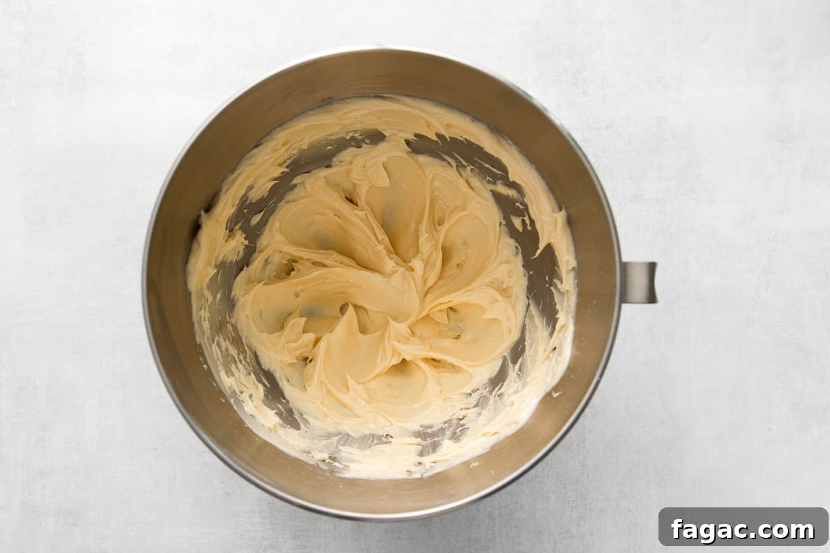 top view of a metal mixing bowl with a yellow batter in it.