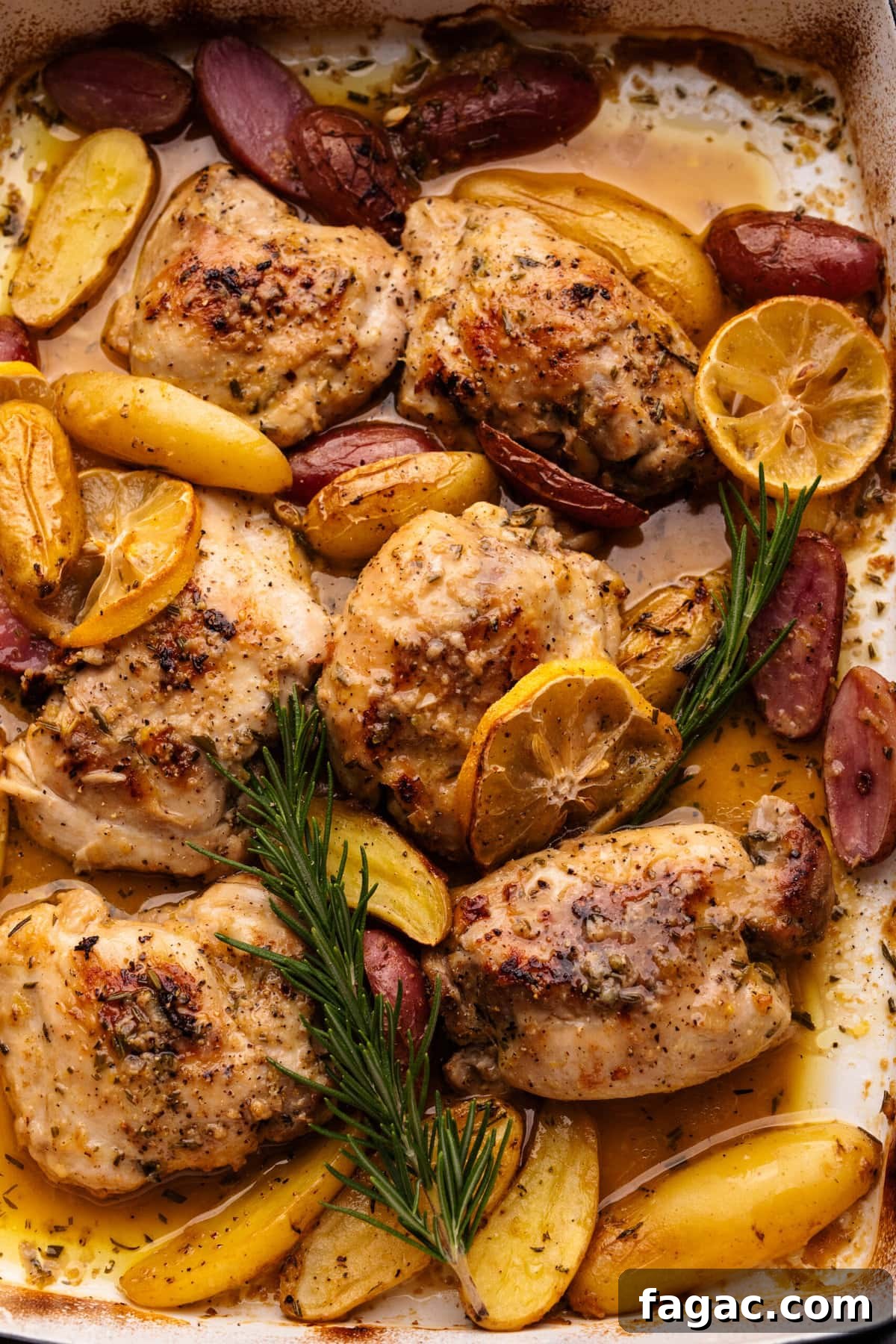 Crispy Roasted Lemon & Rosemary Chicken Thighs with Potatoes 9 A close up of lemon rosemary chicken thighs and potatoes in a roasting pan.