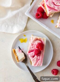 raspberry cheesecake bar on white plate with fresh raspberries and fork taking a piece