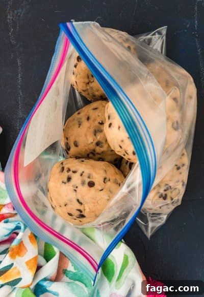 Balls of frozen cookie dough being added to a large ziploc bag.