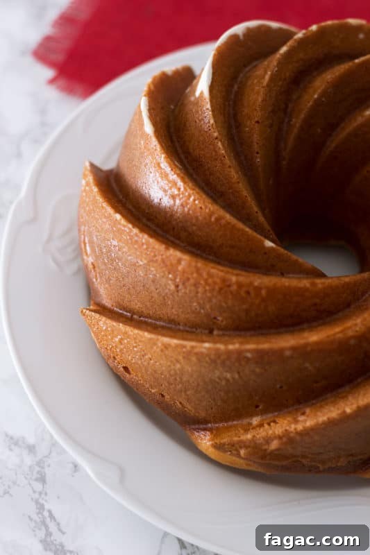 Side view of an Orange Vanilla Bundt Cake sitting on a white plate.