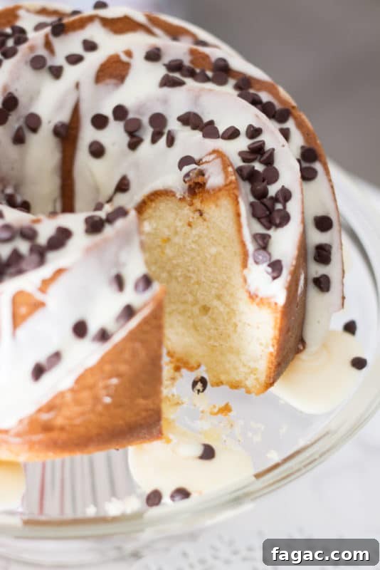 A slice cut out of an Orange Vanilla Bundt Cake topped with cream cheese frostings and chocolate chips.