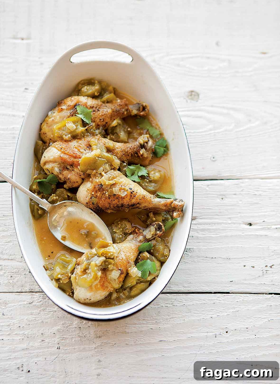 Tangy Braised Chicken with Roasted Tomatillos and Cilantro 2 White oval dish with four chicken drumsticks, chopped green tomatillos, cilantro, onion, sliced chiles.
