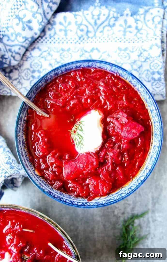Authentic Ukrainian Borscht Recipe: Beet Soup 2 Blue and white bowl filled with red Ukrainian borscht with sour cream dollop on top