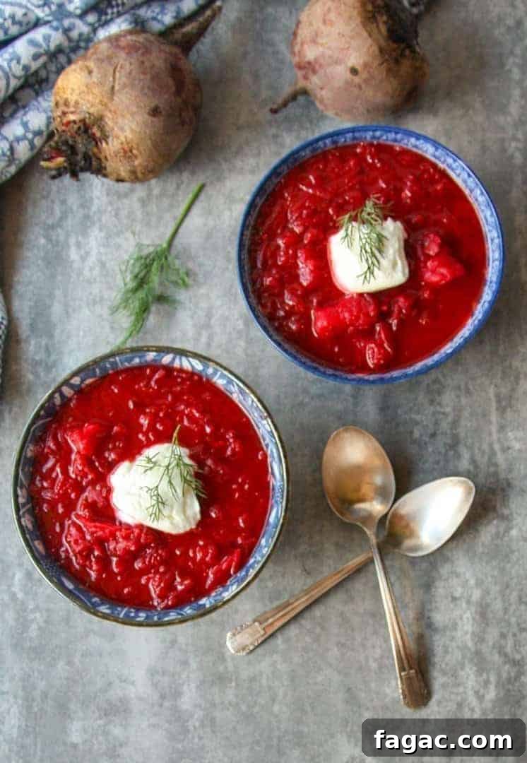 Authentic Ukrainian Borscht Recipe: Beet Soup 7 top shot of red beet soup in two blue bowls with dollop of sour cream on top