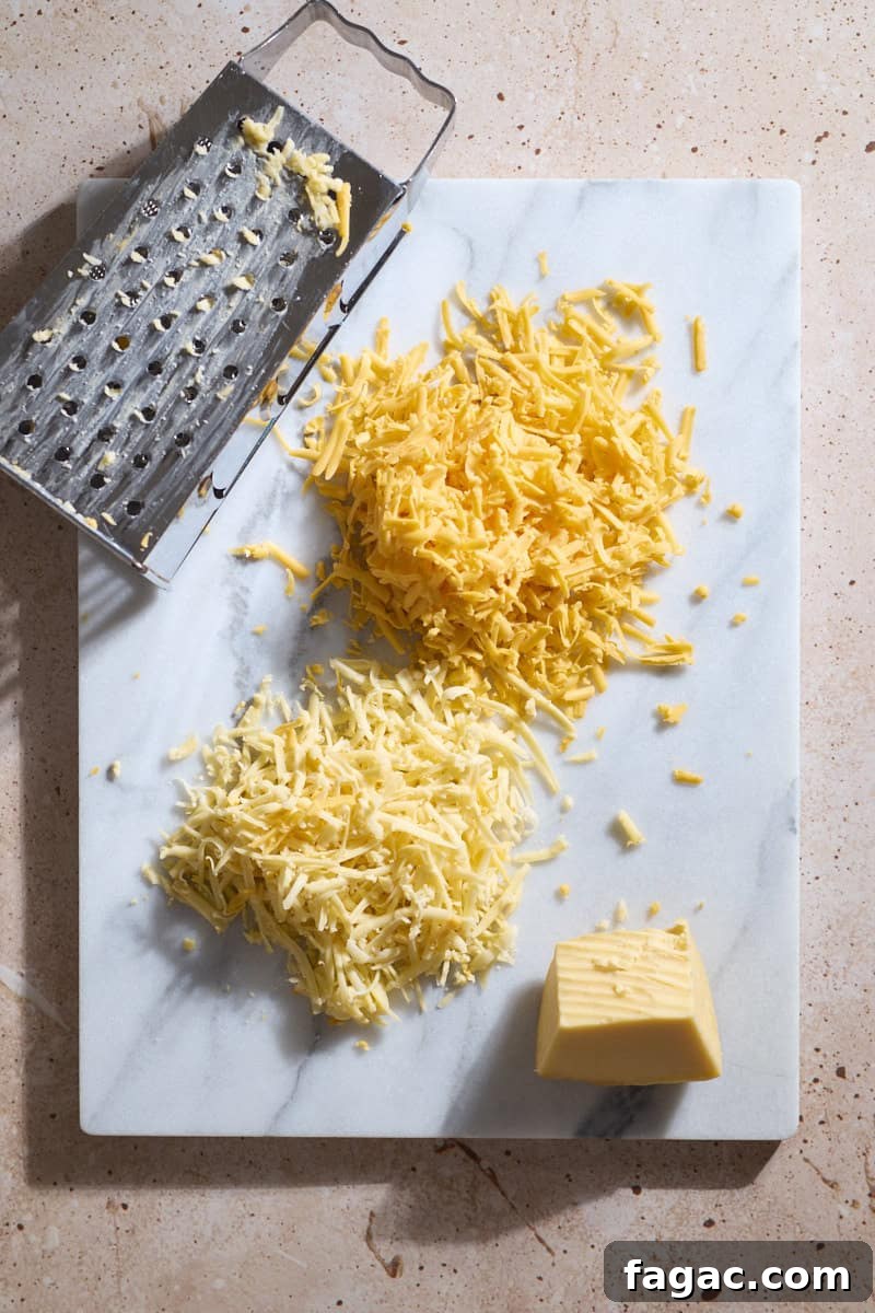 Creamy Beer Cheese Dip for Soft Pretzels 4 Shredded cheese on a white stone board.