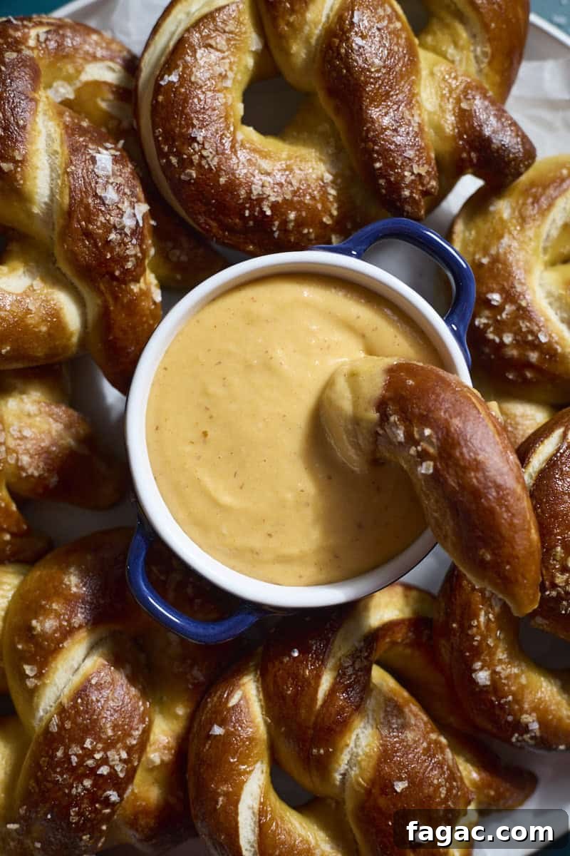 Creamy Beer Cheese Dip for Soft Pretzels 9 A closeup of a bowl of Beer Cheese on a platter of soft pretzels.