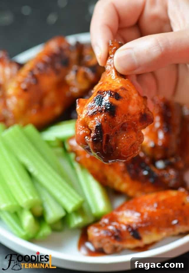 Sticky BBQ Chicken Wings in the Instant Pot 3 holding one bbq sauce chicken drumette with fingers